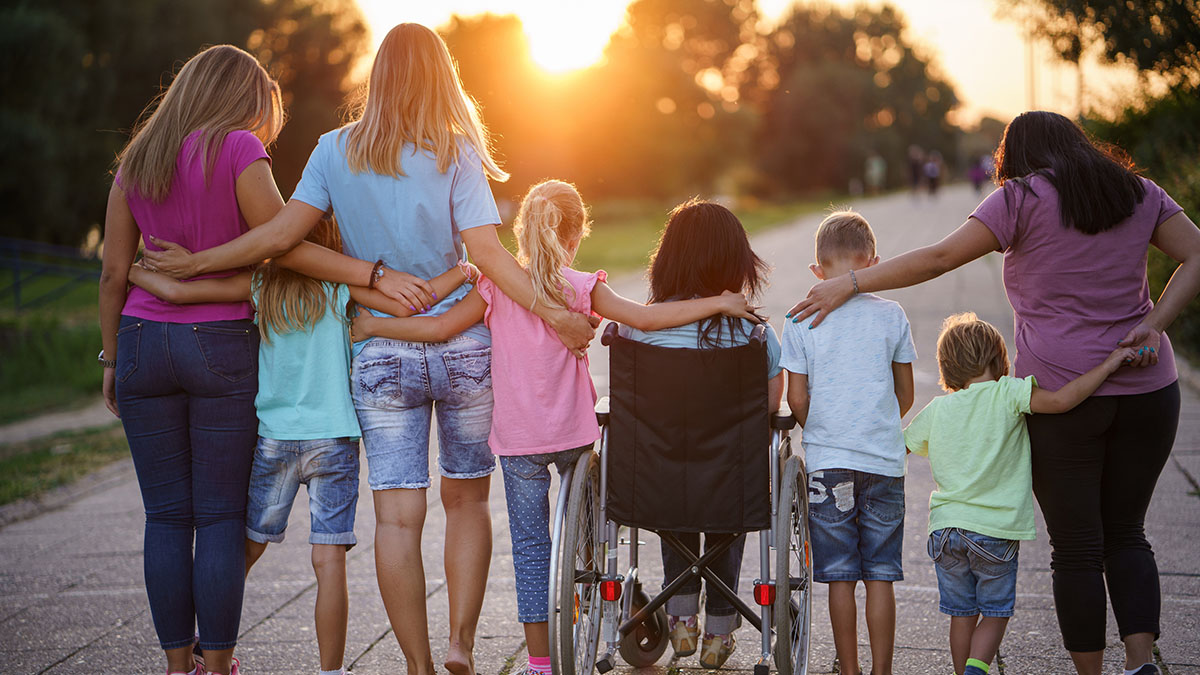 Family with arms around backs watching a sunset