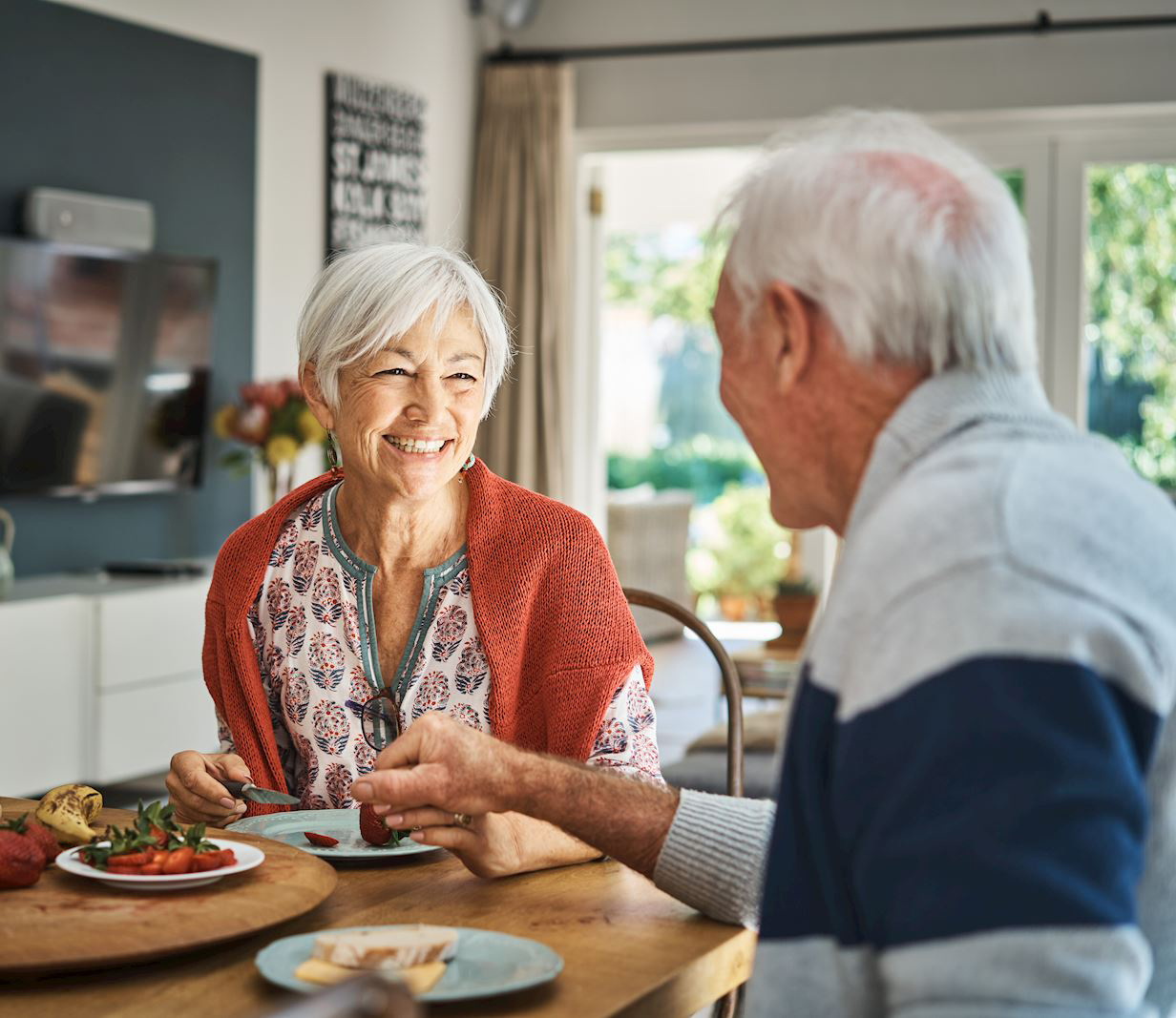 An elderly couple holding hands and looking lovingly at each other as they enjoy their lunch
